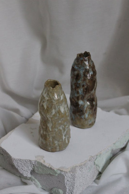 Brun Earth Candleholder fra NIWA vist bag en grøn lysestage