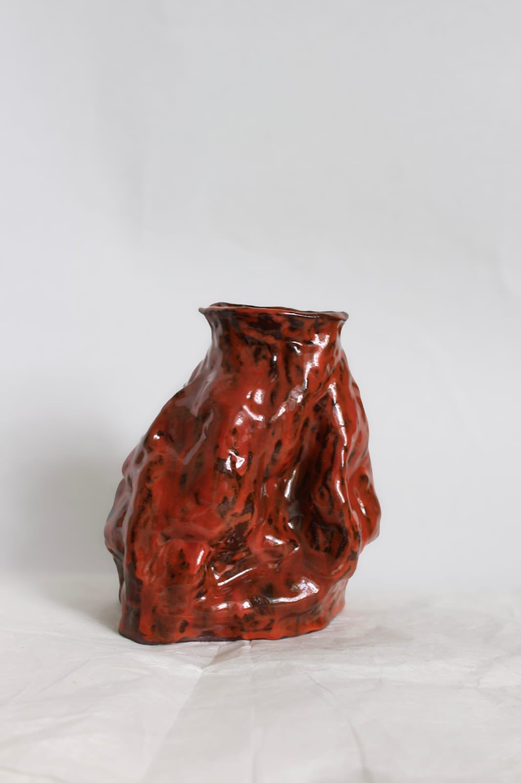 Ember Vessel set fra siden med dybe folder og blank rød glasur