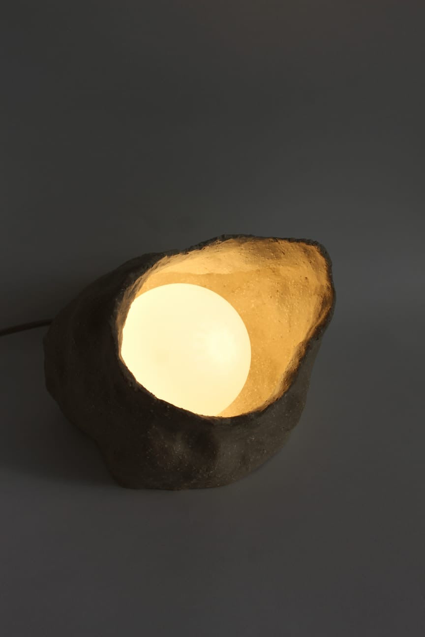 Sand Globe Lamp fra NIWA med tændt lyskugle, der belyser den rå keramiske inderside